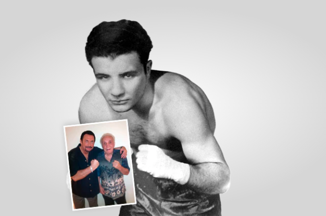 A black and white photo of a young male boxer in fighting stance, showing determination, with a slight smile. He is bare-chested, wearing boxing gloves, and has short, dark hair. In the lower left corner, there is a smaller, color photograph of two men standing together. One man, dressed in a black shirt, has his arm around the shoulder of an elderly gentleman wearing a patterned shirt. Both men are smiling and showing their fists, suggesting camaraderie. The background is a light gray gradient.